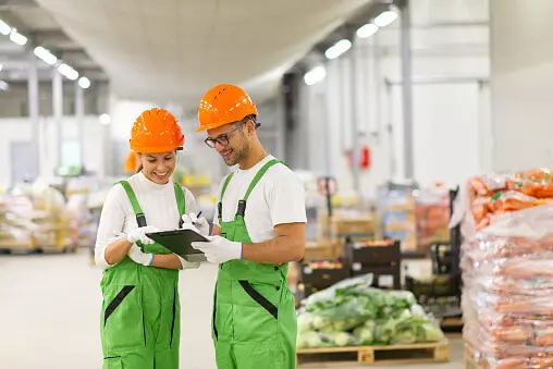 Two workers look at a checklist while standing in a loading bay area