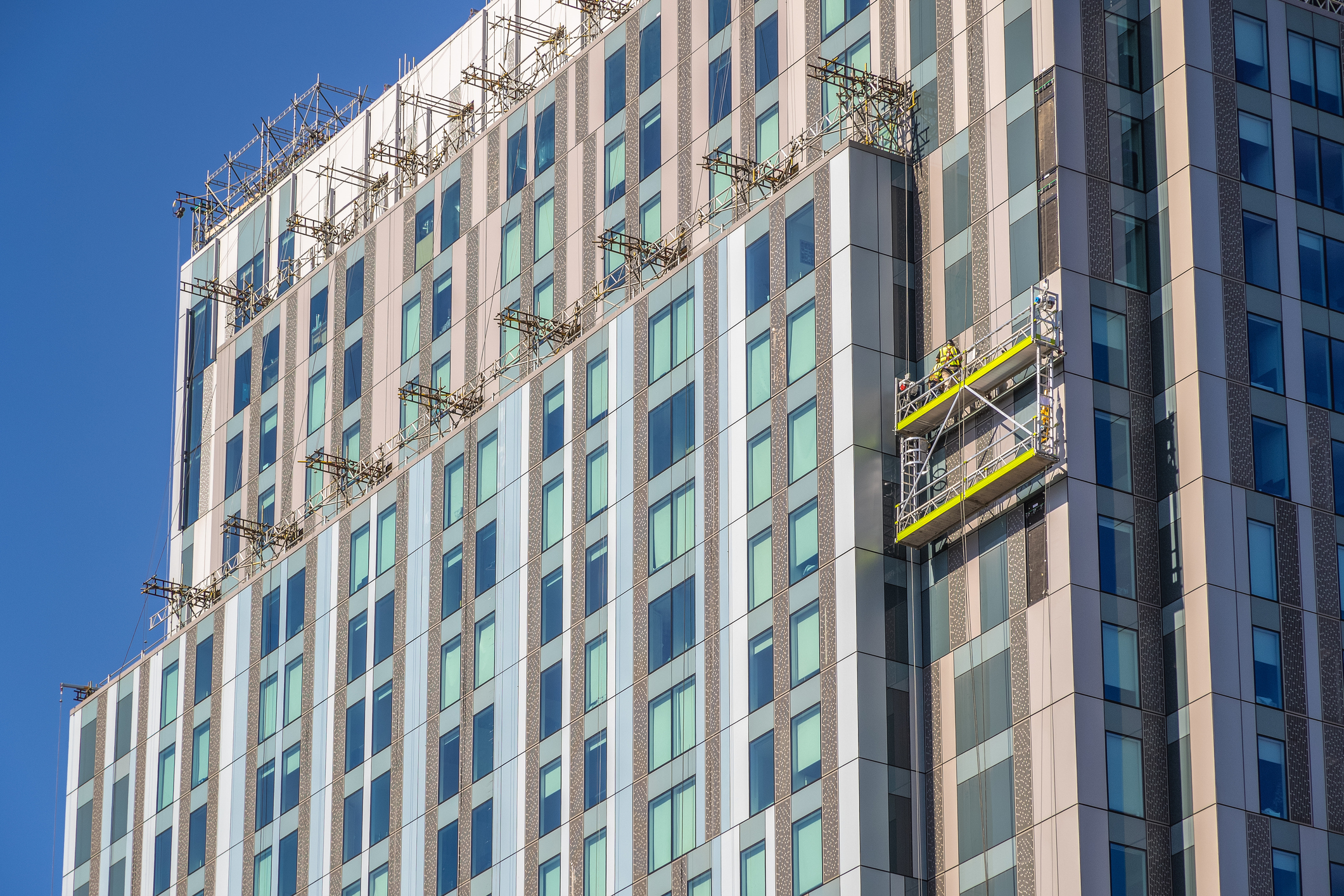 Suspended scaffolding platform with workers on a modern high-rise building façade