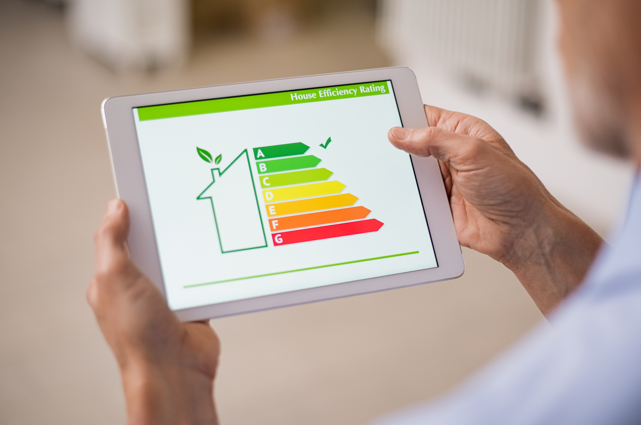 Person holding a tablet displaying a building energy efficiency rating used to assess sustainable commercial building performance