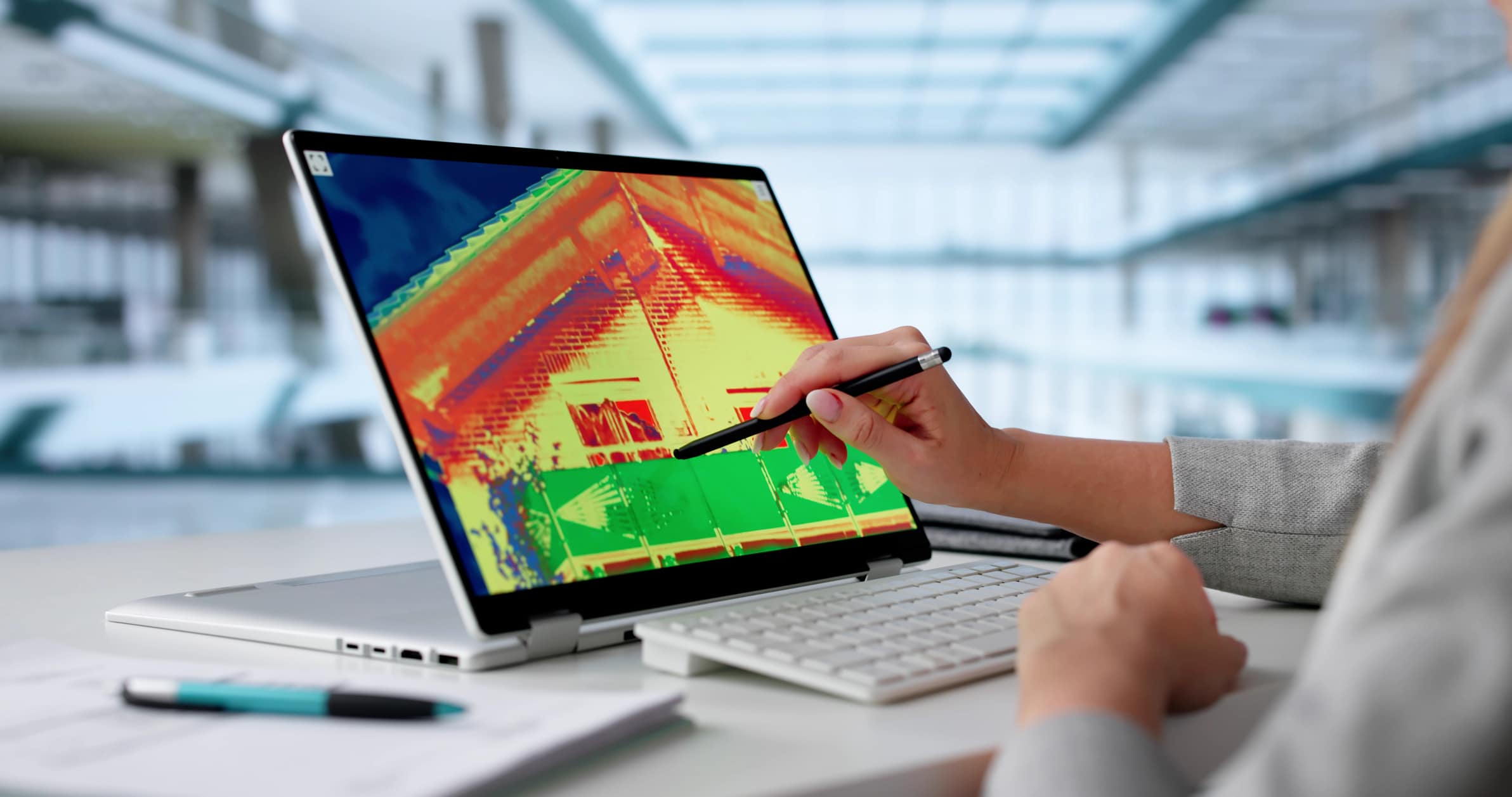 Engineer reviewing a thermal image of a building on a laptop to assess heat loss and identify weak spots in the building envelope