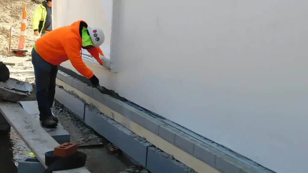 A worker cementing an area in a thermal break construction site.